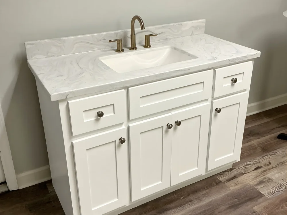 White bathroom vanity with marble countertop and brushed brass faucet, modern shaker-style cabinet by Artistic Marble