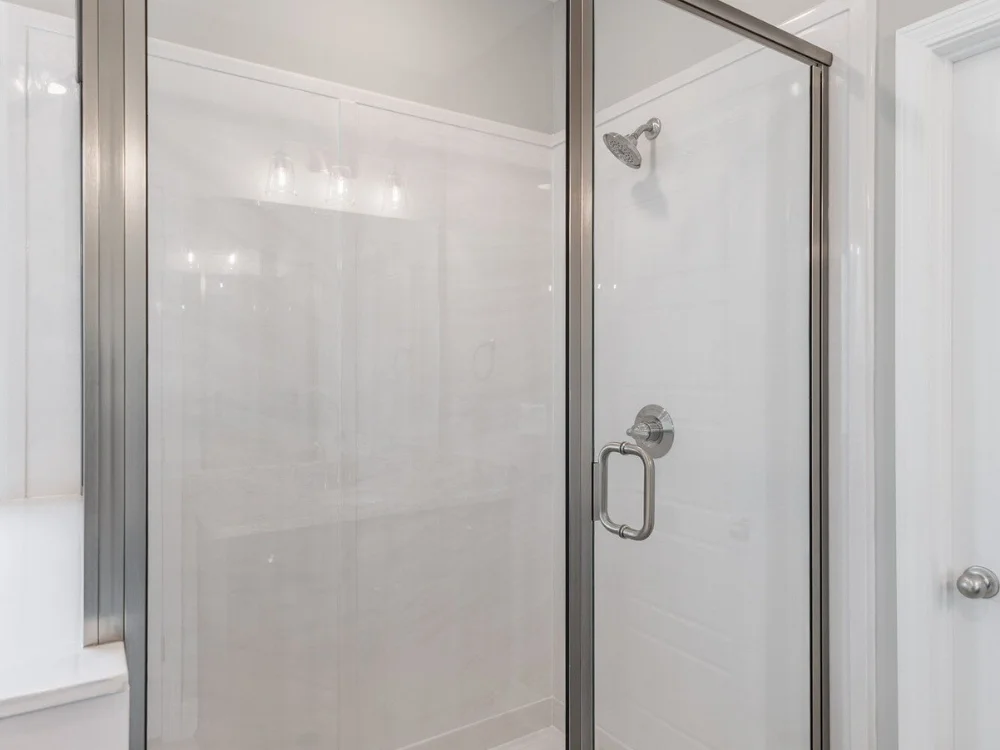 Elegant walk-in shower featuring white cast marble surround and clear glass enclosure in Huntsville Alabama