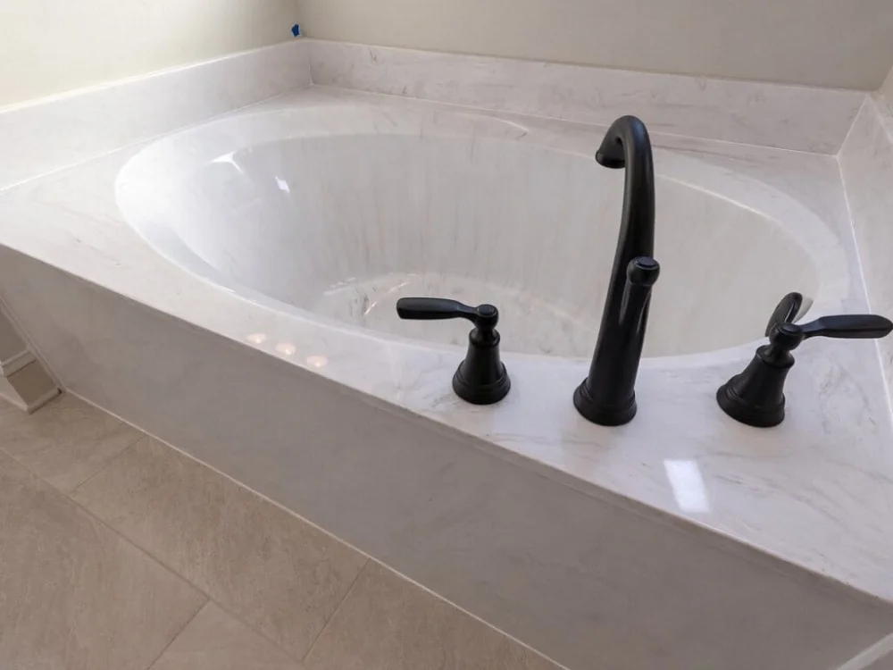 Luxury bathroom tub with cast marble surround and modern matte black fixtures in Huntsville Alabama
