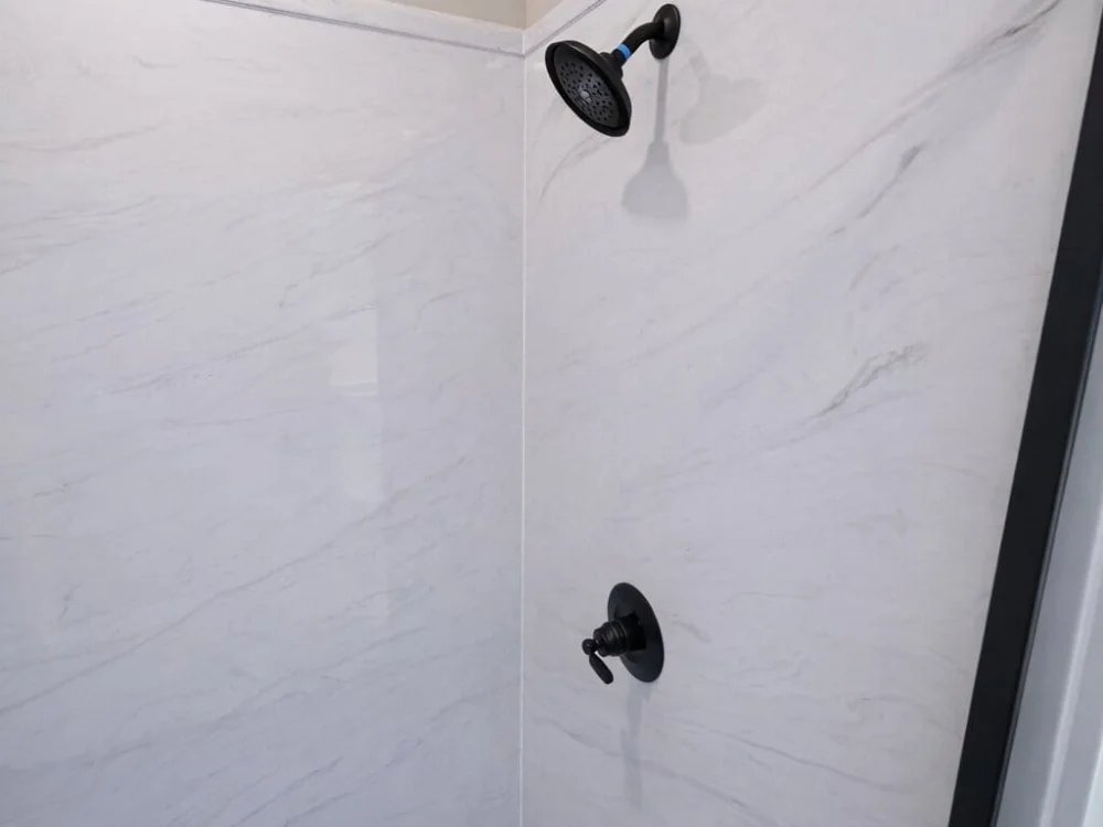 White cast marble shower wall panels with matte black shower fixture in Huntsville, Alabama